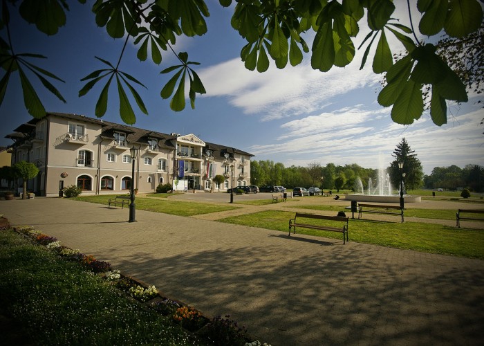 A szálloda, háttérben a szökőkút és a park, valamint a parkoló